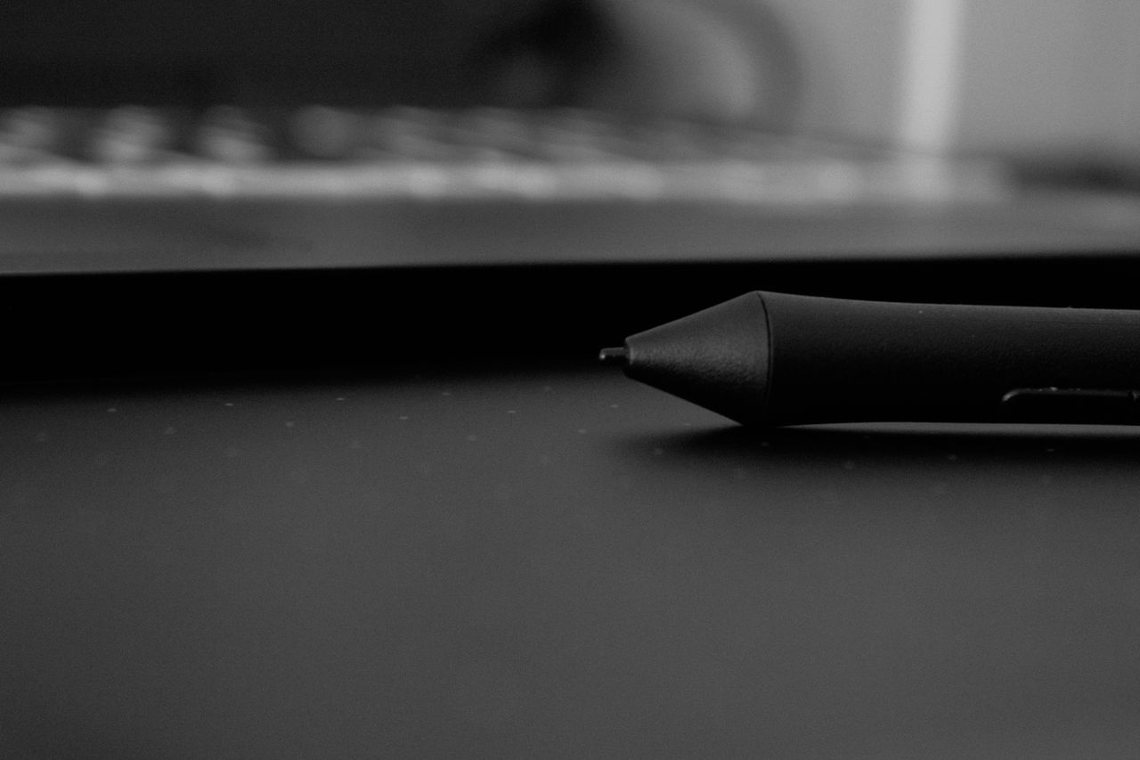 A black and white close-up of a stylus pen on a digital drawing tablet, ideal for tech themes.